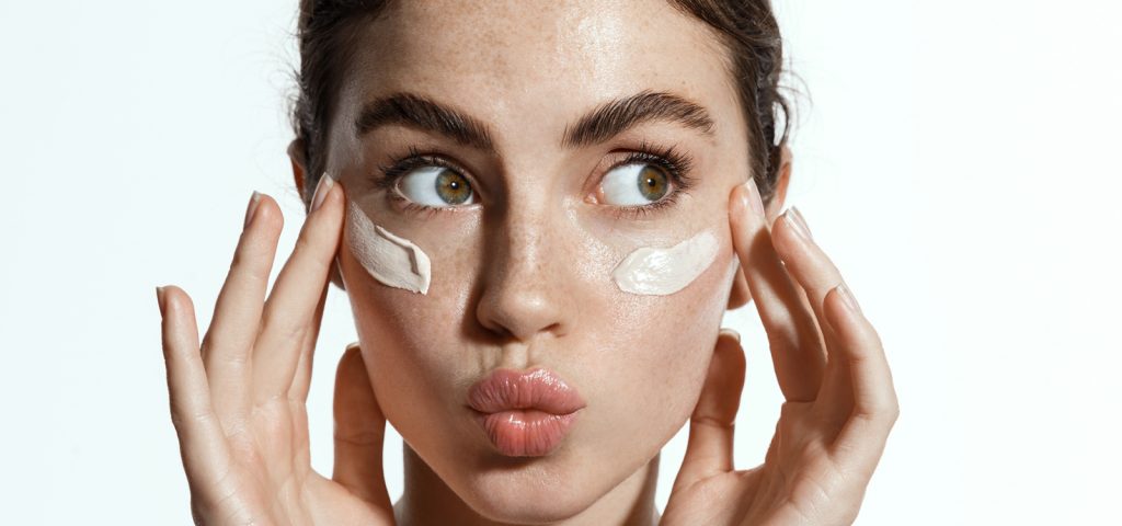 Brunette woman applying daily sunscreen to her face